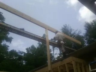 Carpenter setting a ridge beam over a new addition frame — Ice Dam Removal by Roofing Brothers in Cohasset