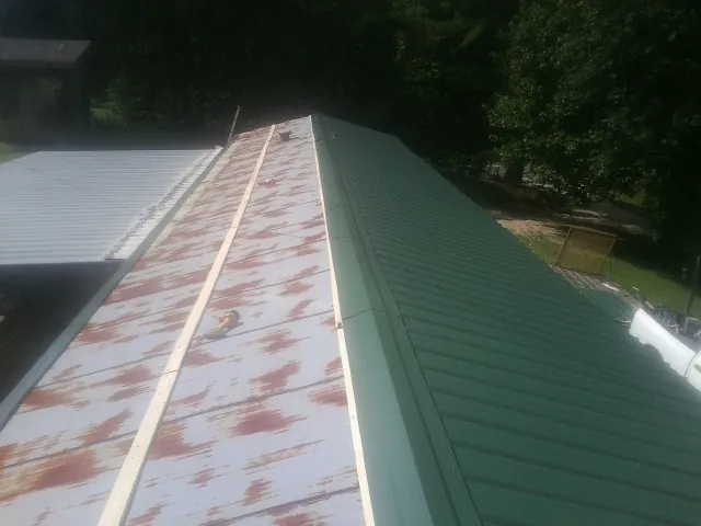 Old rusted panels beside newly installed green metal roofing — Wind Damage Roof Repair by Roofing Brothers in Cohasset