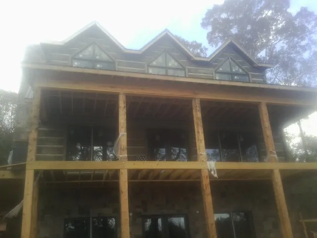 Dormers and porch framing on a large log home under construction — Roof Coating work by our crew in Cohasset