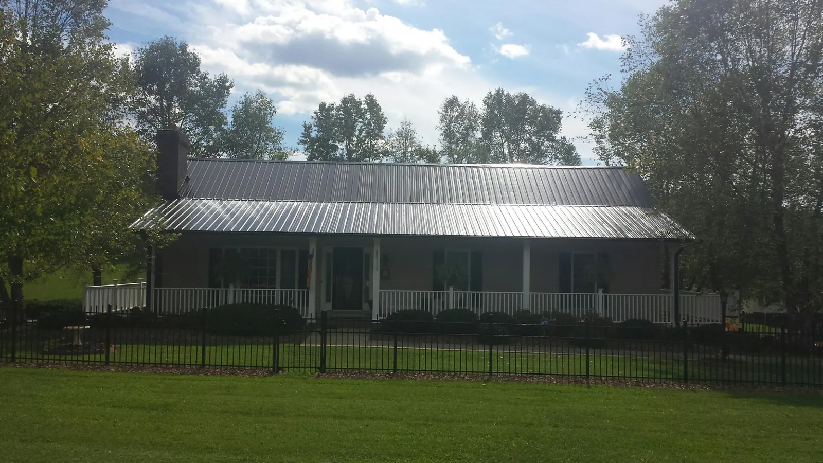 Gray metal roof on a brick ranch with a full width front porch — Gutter Guard Installation work by our crew in Cohasset
