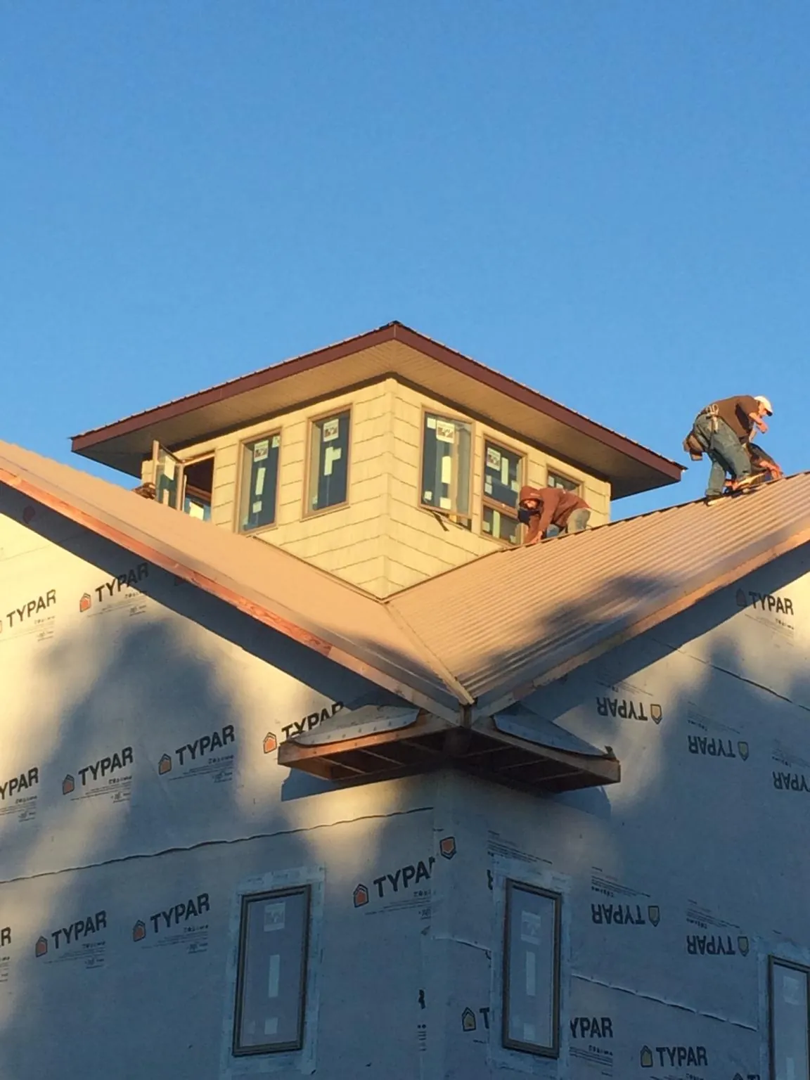 Roofers working around a rooftop cupola on a new metal roof at sunset — Roof Waterproofing in Cohasset by Roofing Brothers